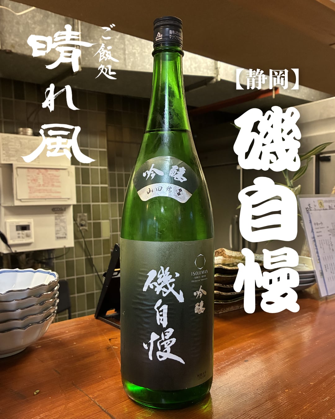 店主が選ぶ静岡の日本酒「磯自慢」吟醸の一升瓶。カウンターに置かれた緑瓶に筆文字の店名入り